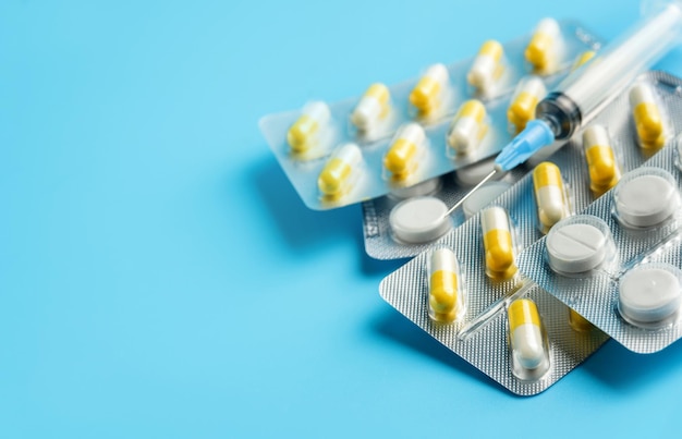 various medicines in blisters and syringes on a blue background with copy space. Medicines close-up with selective focus and copy space.