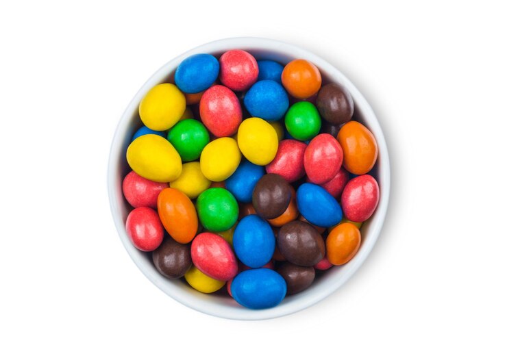 Photo various milk chocolate sweet candies with a rice centre in a sugar shell on white background top view