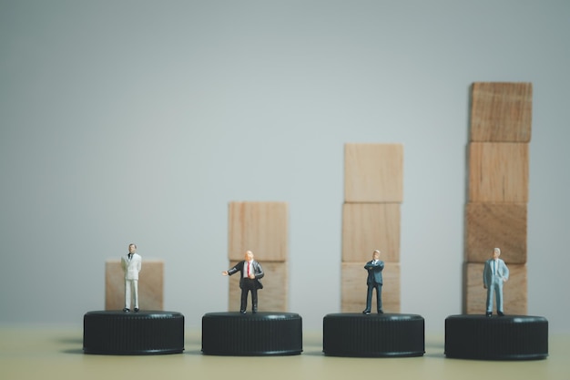 various of miniature businessman standing in front of a wooden block chart