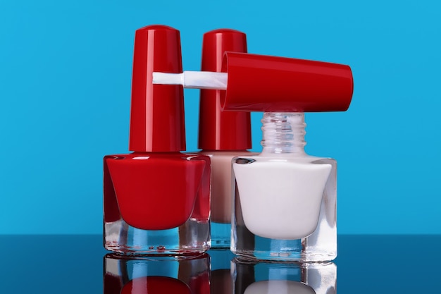 Various nail polish bottles on blue background selective focus.