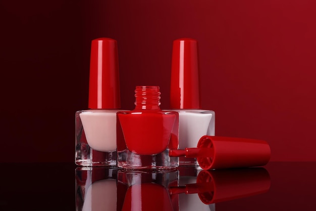 Various nail polish bottles on red background selective focus