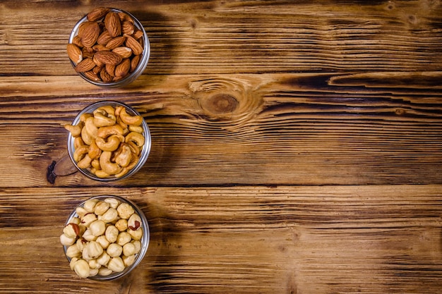 Various nuts almond cashew hazelnut in glass bowls on a wooden table Vegetarian meal Healthy eating concept Top view