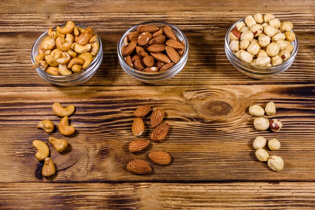 Various nuts almond cashew hazelnut in glass bowls on a wooden table Vegetarian meal Healthy eating concept