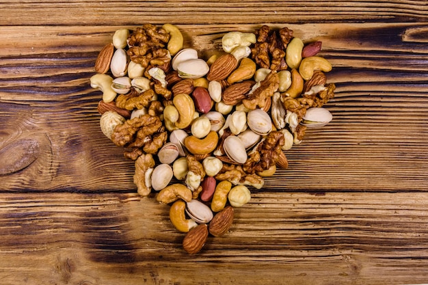 Various nuts almond cashew hazelnut pistachio walnut in shape of heart on a wooden table Vegetarian meal Healthy eating concept