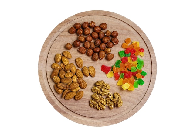 Photo various nuts and candied fruits on a round wooden cutting board