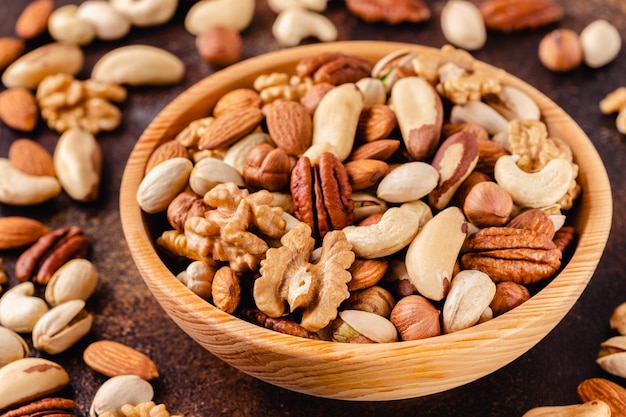 Various Nuts in wooden bowl on dark background