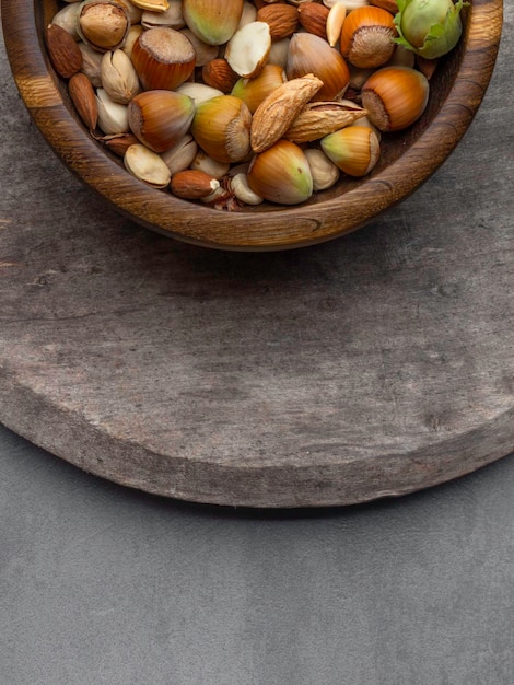 Various nuts in wooden bowls on dark wooden background Almonds pistachios hazelnut and pumpkin seeds Top view