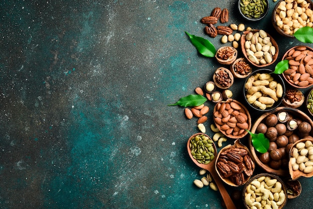 Photo various nuts in wooden bowls top view on a dark background