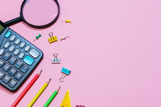 Photo various office supplies on a pink background back to school concept view from above calculator and p...