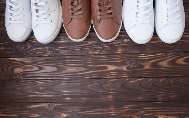 Various pairs of colorful sneakers laid on the wooden floor background