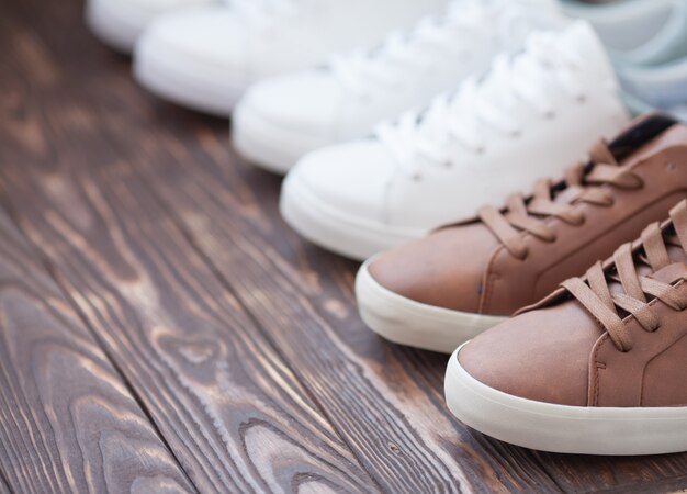 Various pairs of colorful sneakers laid on the wooden floor background