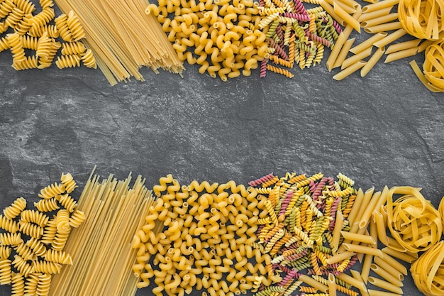 Various pasta on dark stone background