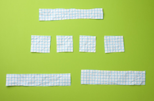 Various pieces of white paper in a blue cage on a green surface. surface for inscriptions