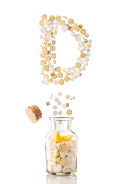 Various pills fly out of a glass jar in the form of letter D, isolated on white background