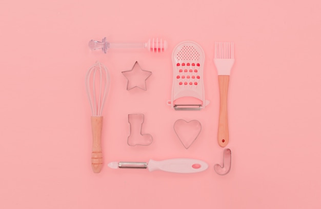 Various pink kitchen utensils on abstract pink background. Greater, whisk and iron cooking form. Top horizontal view copyspace love cookong concept