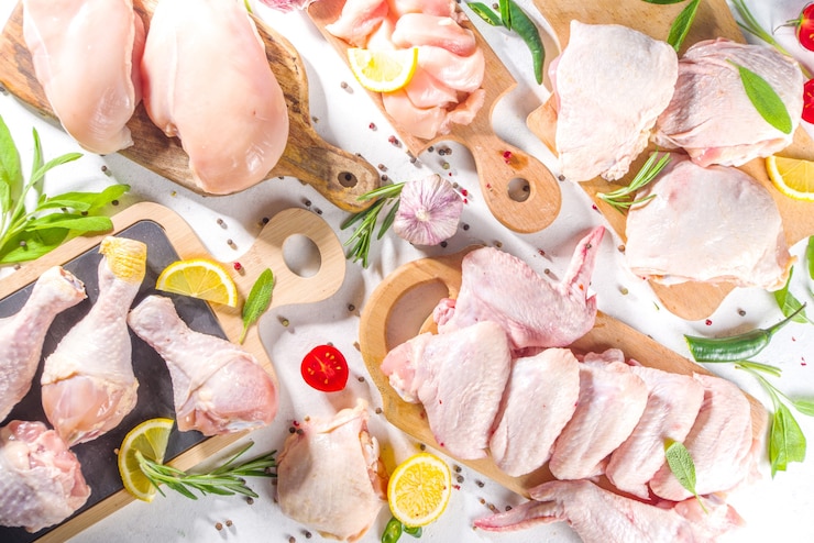 Фотография различные порции сырого куриного мяса. набор сырого куриного филе, бедра, крыльев, полосок и ножек на белом фоне кухонного стола со специями