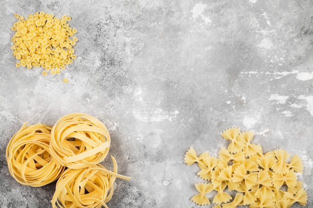 Various raw pasta on gray background. Top view, copy space. Food background