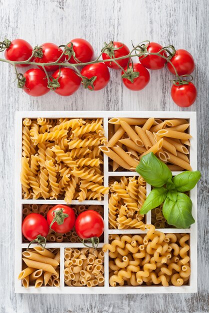 Various raw wholegrain pasta in white wooden box