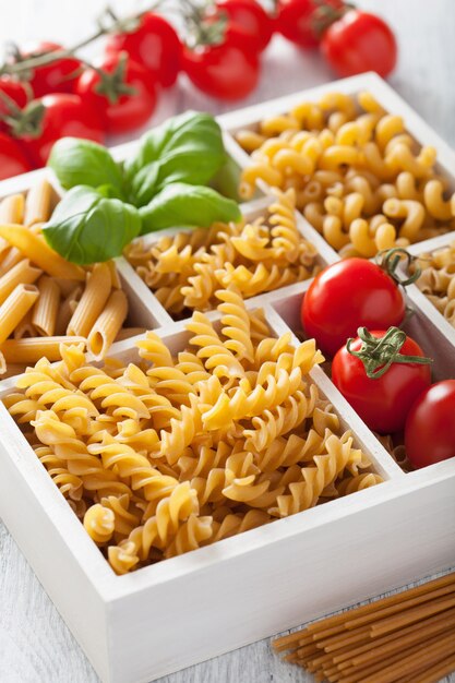 Various raw wholegrain pasta in white wooden box