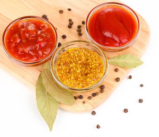 Various sauces on chopping board isolated on white