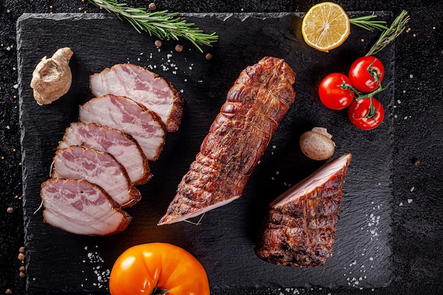 Various sausages and smoked products lie on a black board