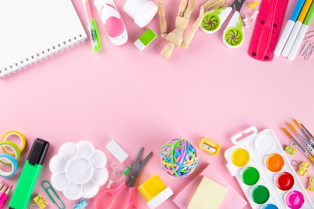 Various school office and painting supplies on pink background