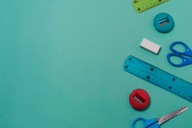 Various school supplies on green background