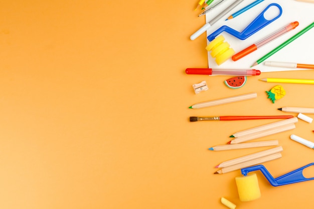 Various school supplies on orange surface