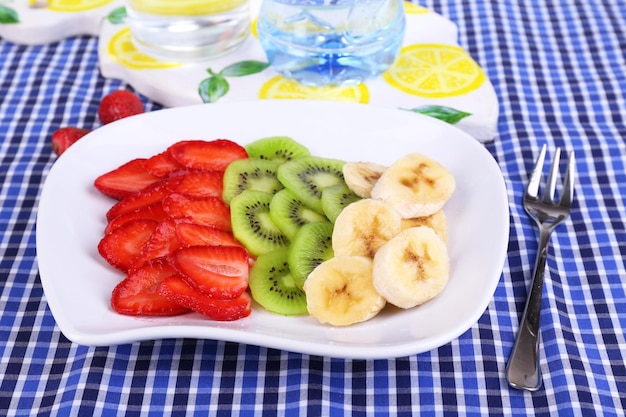 Various sliced fruits on plate on napkin closeup