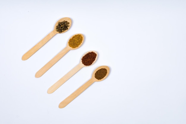 Various spice seeds in wooden spoons on a white background diagonally Seeds of beet mustard lettuce rukla on a white background Place for an inscription View from above