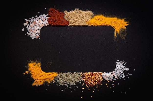 Various spices on black background top view with copy space