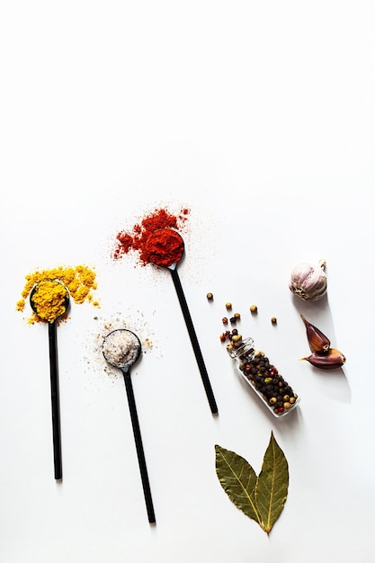 Various spices in black spoons