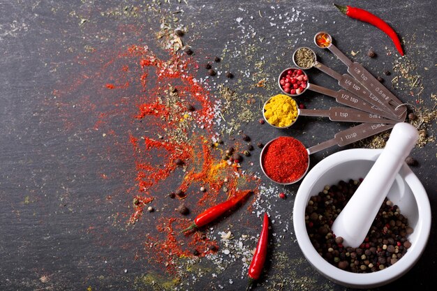 Photo various  spices for cooking on dark table, top view