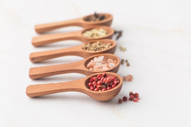 Various spices and green herbs in wooden spoons on white table high quality photo