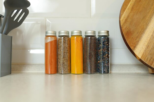 Photo various spices in jars against the wall on a modern kitchen table with copy space