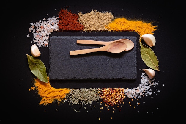 Various spices spoons on black background with copy space top view