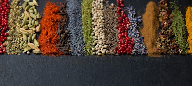 Various spices spoons on black table. Top view with copy space