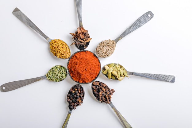 Various spices in spoons on white background