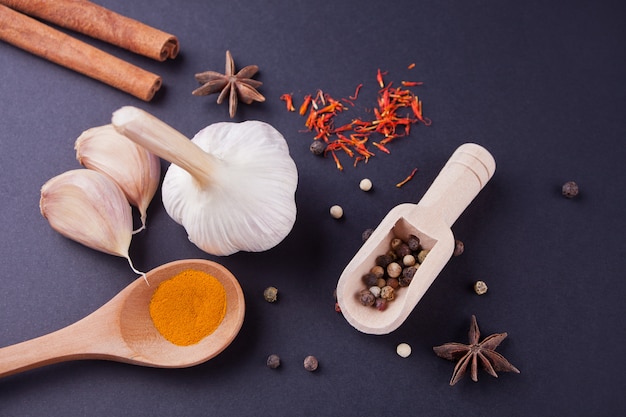 Various spices with wooden spoons on a black table