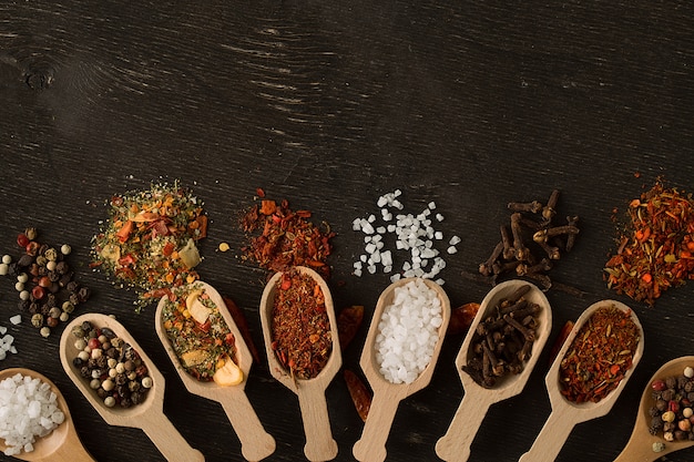 Various spices in wooden spoons  on dark wooden table