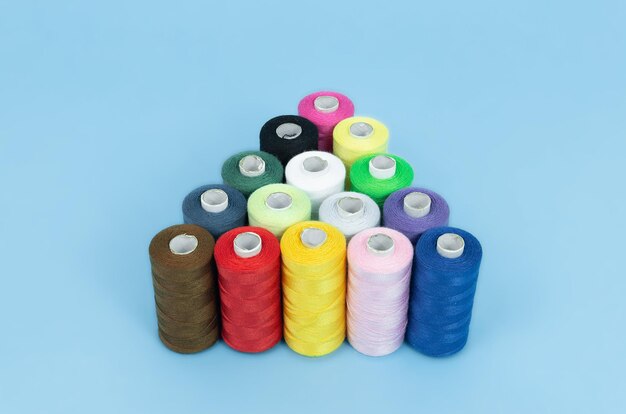 Photo various spools of sewing cotton thread of different colors on colored background