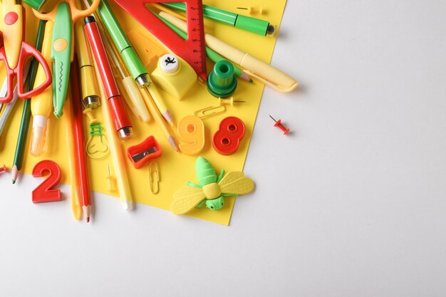 Vari elementi di cancelleria di colore rosso giallo e verde sono al centro su sfondo beige ritorno a scuola spazio per la copia posizione piatta vista dall'alto