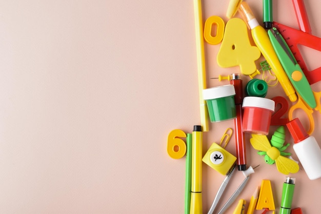 Vari articoli di cancelleria di colore rosso giallo e verde sono al centro su uno sfondo beige ritorno a scuola