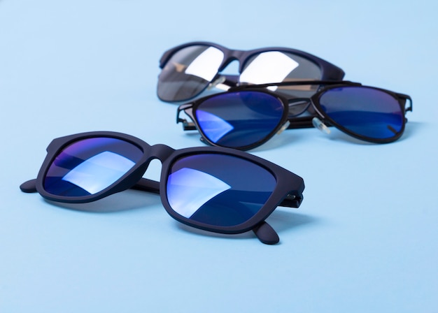 Various stylish sunglasses on blue creative table