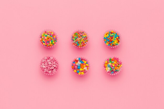 Various sugar sprinkles on pink background
