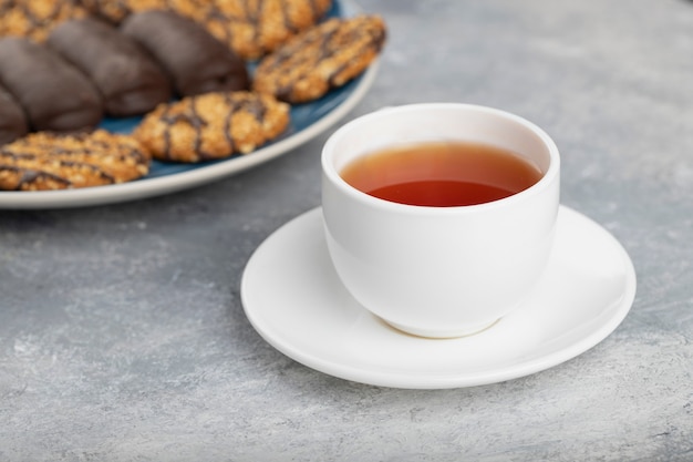 Various sweet snacks with cup of hot tea placed on a stone table .