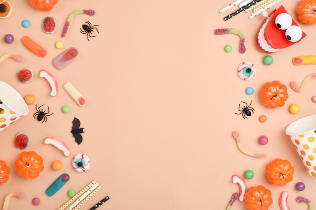 Various sweets on an orange background with a place for text. Background for the Halloween holiday. Flat layout, top view, a place to copy.