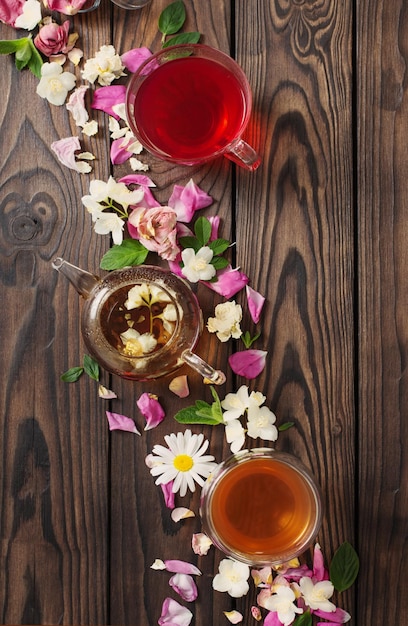 Various teas with herbs and flowers on a dark wooden table top view