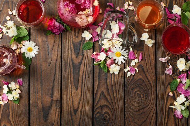 Various teas with herbs and flowers on a dark wooden table top view