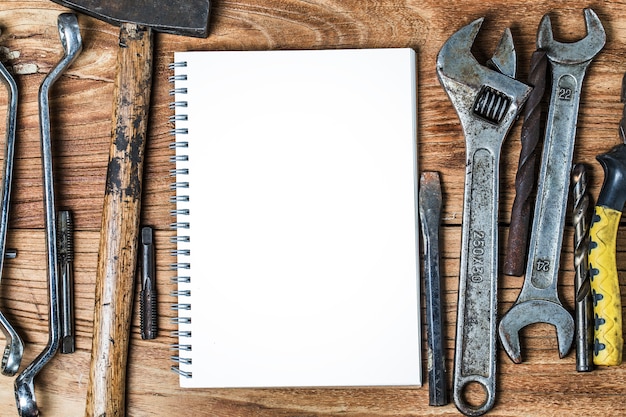 Photo various tools and the blank notebook on a wooden background